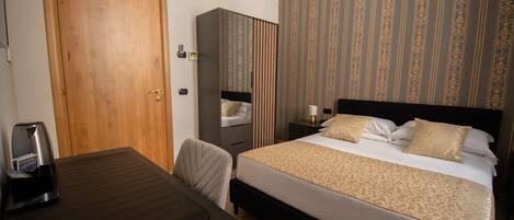 A hotel room with a bed, a desk, a wardrobe, and a coffee maker.