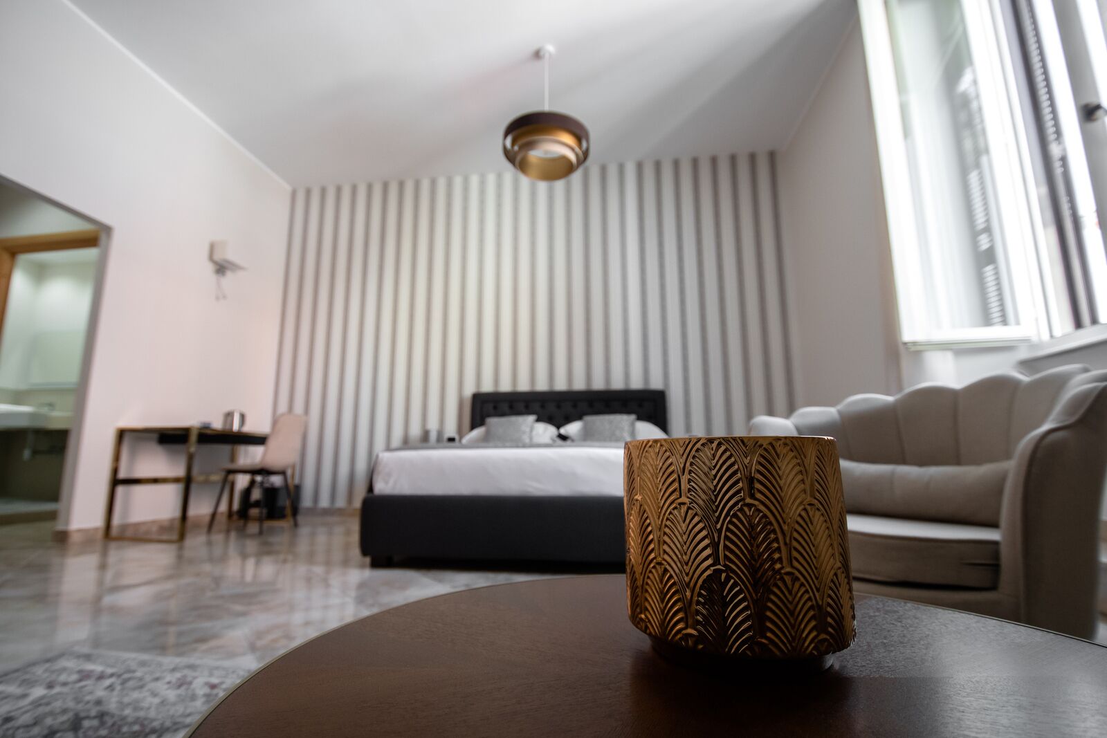 A modern bedroom with a bed, a sofa, a table, and a decorative vase.