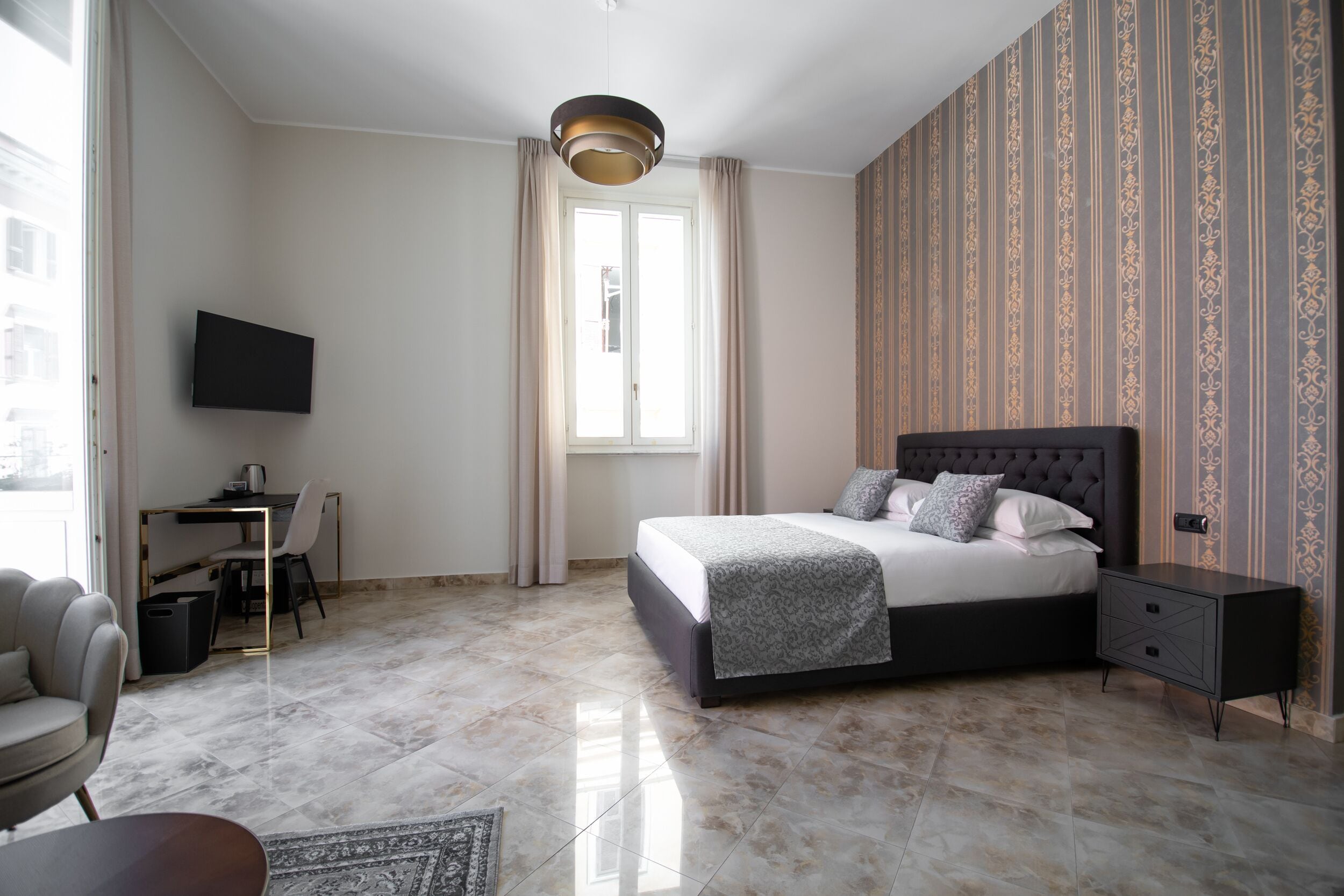 Une chambre à coucher avec un lit, un bureau, une chaise, un téléviseur et une fenêtre avec des rideaux.