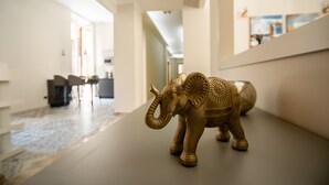 Una escultura de elefante dorado sobre una mesa en un pasillo moderno y bien iluminado, con una cocina al fondo.