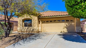 A residential house with a garage, a driveway, and a tree in the foreground. - Entire home ~ Quiet Getaway ~ Spacious and Comfortable ~ Chef's Kitchen! (Tucson)