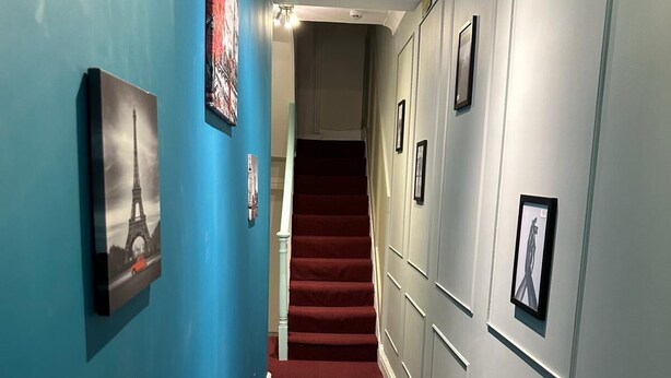 A hallway with blue walls, red carpet, and a staircase leading to an upper floor. - Acton Vale hotel  (London)