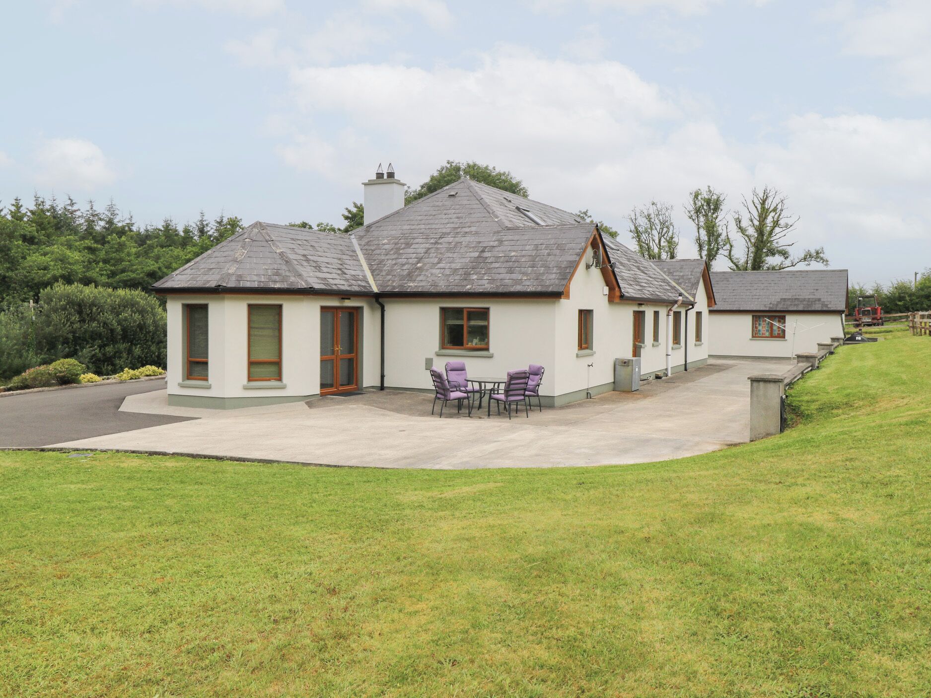 A row of white cottages with grey roofs, each featuring a small patio with outdoor seating.