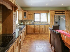 A kitchen with wooden cabinets, a black countertop, a stainless steel sink, and a dining area with a table and chairs.