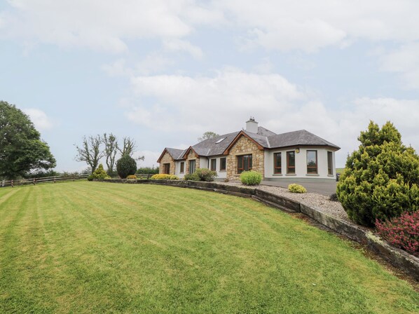 A two-story house with a stone facade, a sloped roof, and a well-maintained lawn.