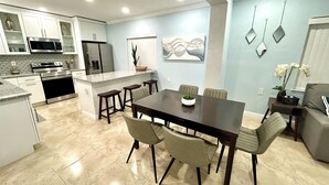 A modern kitchen with white cabinets, a stainless steel refrigerator, and a built-in oven.
