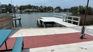 A waterfront park with a dock, benches, and a paved walkway.