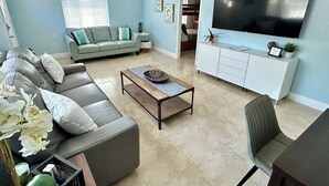 A living room with a grey sofa, a coffee table, a TV, and a white cabinet.