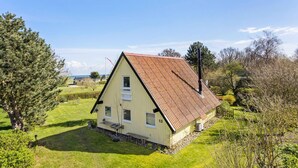 Una casa a un piano con tetto spiovente, un camino e un piccolo portico.