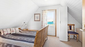 Una camera da letto con due letti singoli, una scrivania, una sedia, una lampada e una porta che dà su un balcone.