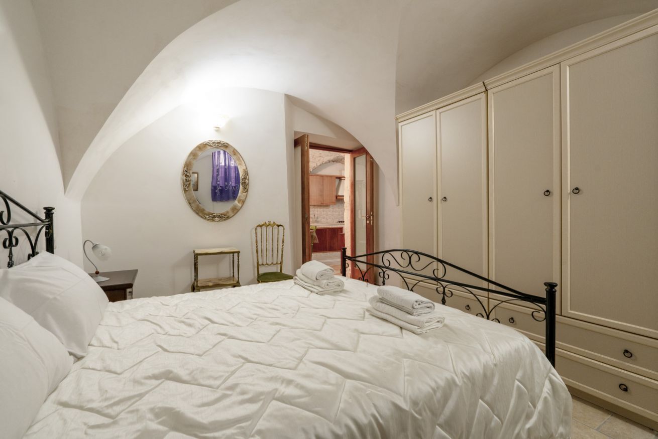 Une chambre à coucher comprenant un lit, un miroir, une armoire et une porte donnant sur une autre pièce.