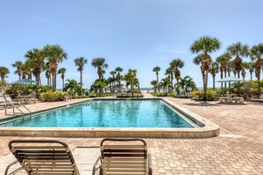 Relax by the pool with ocean views, surrounded by palm trees and lounge chairs.
