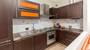 A modern kitchen with dark wooden cabinets, stainless steel appliances, and a tiled backsplash. - GuestHost - The apartment, a welcoming residence of approximately 70 square meters, is ideal for hosting up to 4 people. Located on the first floor of a building with elevator in the Washington district, one of the most elegant residential areas of Milan (Milano)