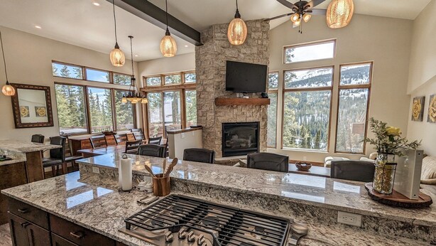 A spacious kitchen with a large island, granite countertops, and a gas stove. There are multiple windows providing natural light and views of the outdoors. - Hot Tub & Mtn Views - Modern Build, Pet-Friendly, 14 mi to Breck (Alma)