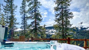 A hot tub with a wooden deck, surrounded by tall pine trees and a snowy mountain backdrop. - Hot Tub & Mtn Views - Modern Build, Pet-Friendly, 14 mi to Breck (Alma)