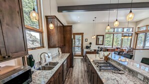 A spacious kitchen with granite countertops, wooden cabinets, and a central island with a built-in stove. - Hot Tub & Mtn Views - Modern Build, Pet-Friendly, 14 mi to Breck (Alma)