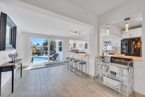 A modern kitchen with a bar area, large windows, and a view of the outdoor pool.