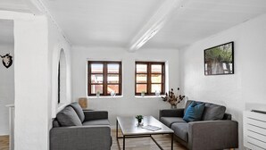 A modern living room with two grey sofas, a coffee table, and two windows with wooden frames. - 4 bedroom awesome home in Rudkøbing (Rudkøbing)