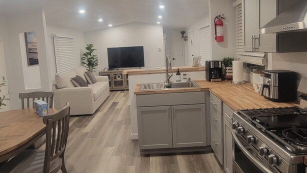 A modern kitchen with a central island, built-in oven, and a dining area with a wooden table and chairs.