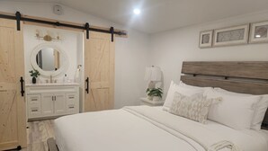 A bedroom with a bed, a nightstand, a mirror, a dresser, and a sliding door.