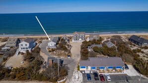 Vista aérea de una zona residencial costera con casas, una playa y una vista despejada del océano.