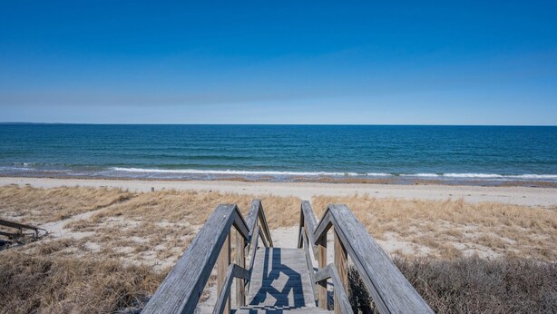 Un paseo marítimo de madera que conduce a una playa con vista despejada al océano.