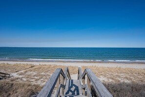 A wooden boardwalk leading to a beach with a clear view of the ocean.