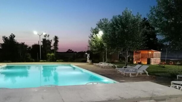 Une piscine avec des chaises longues et un petit bâtiment en arrière-plan.