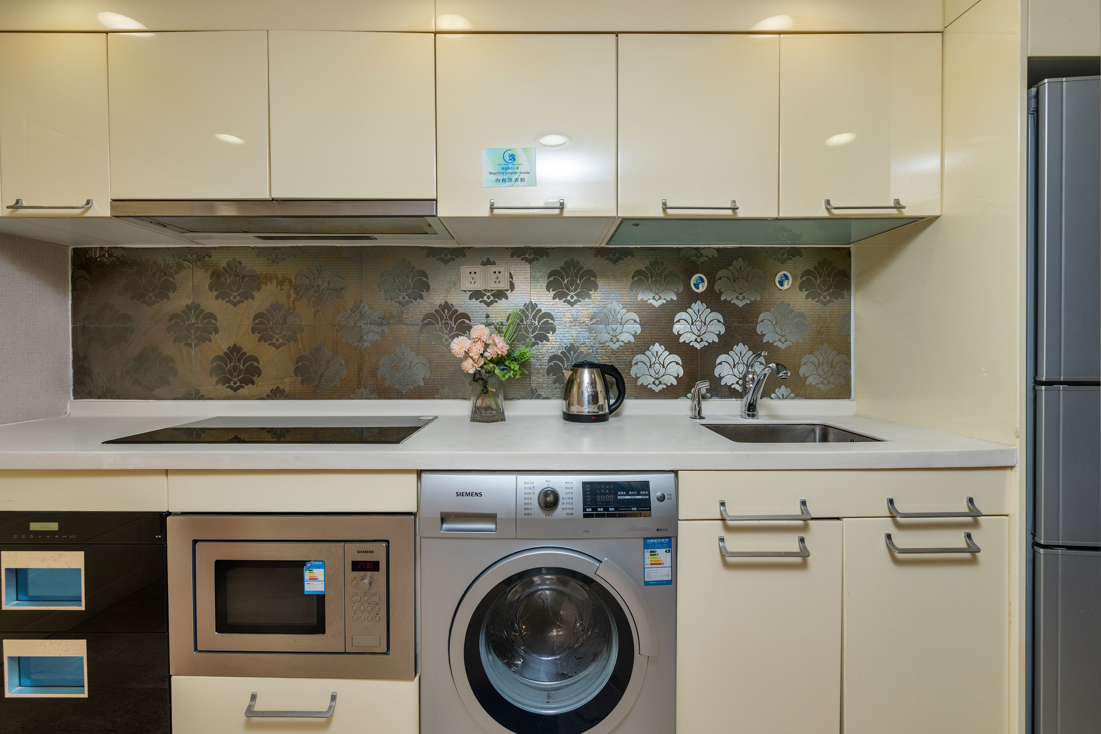 A compact kitchen with a washing machine, microwave, and a sink.
