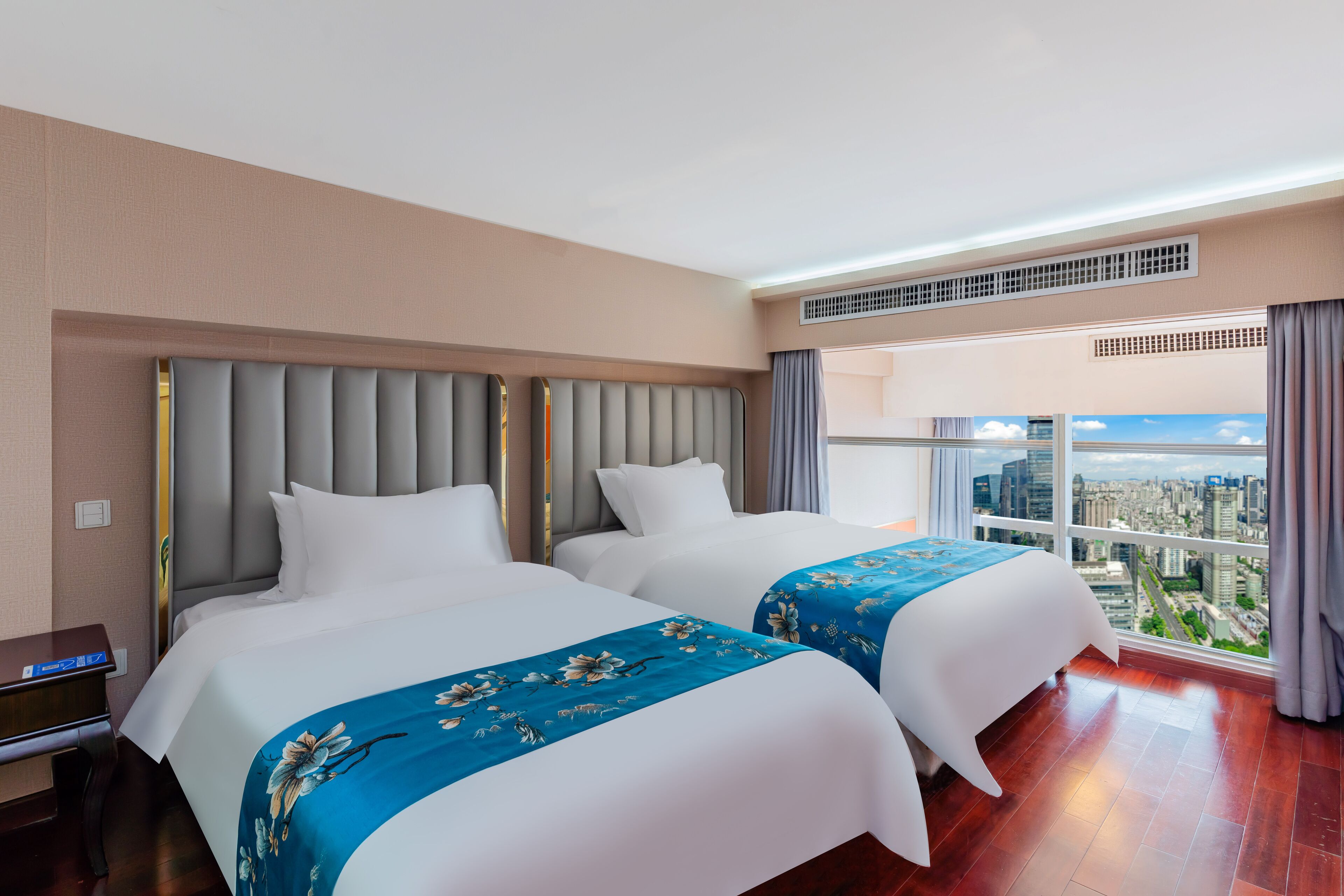 A hotel room with two beds, a city view, and a modern design.