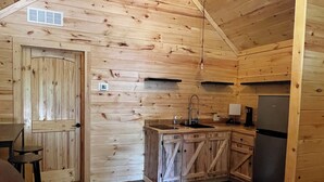 Acogedor interior de cabaña con detalles de madera, un sofá, una zona de cocina y una mesa de comedor.