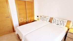 A bedroom with a wooden wardrobe, a bed with white bedding, and a nightstand. - Lovley Ground Floor 2 Bed with direct access to the Pool, Free WiFi (Sucina)