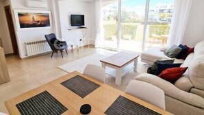 A modern living room with a sofa, a coffee table, and a TV. - Lovley Ground Floor 2 Bed with direct access to the Pool, Free WiFi (Sucina)