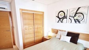A bedroom with a bed, a wooden wardrobe, and abstract wall art.