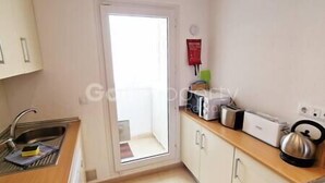 A small kitchen with a sink, a toaster, and a kettle on the counter.