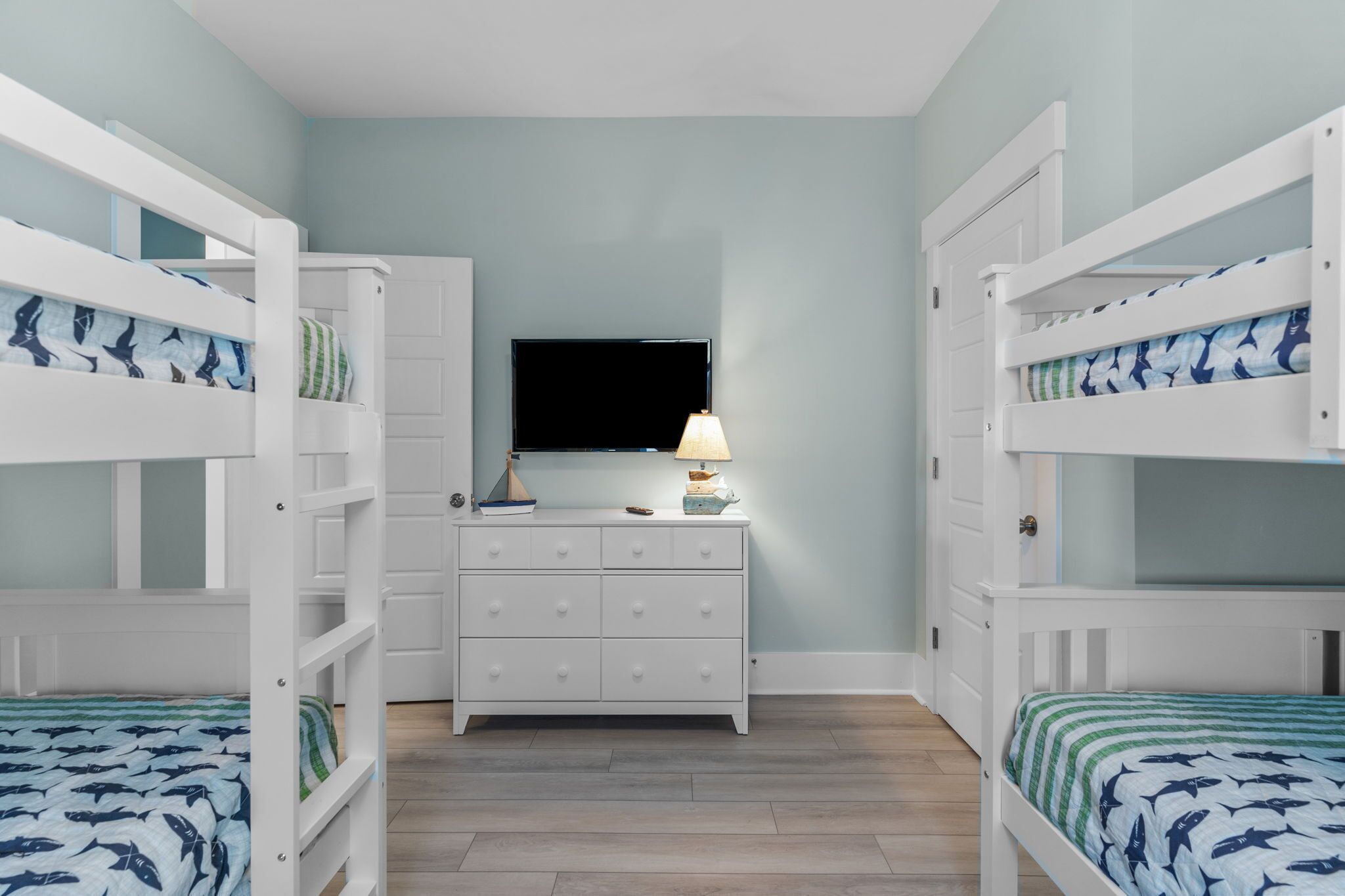 A bedroom with bunk beds, a dresser, a TV, and a lamp.