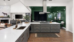 A modern kitchen with a large island, a fireplace, and a green accent wall.