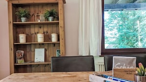 A wooden table with a tray, a bookshelf with potted plants, and a window with a view of trees. - Cosy apartment in villa for 4 people with WIFI, TV, terrace and pets allowed (Bad Wildungen)