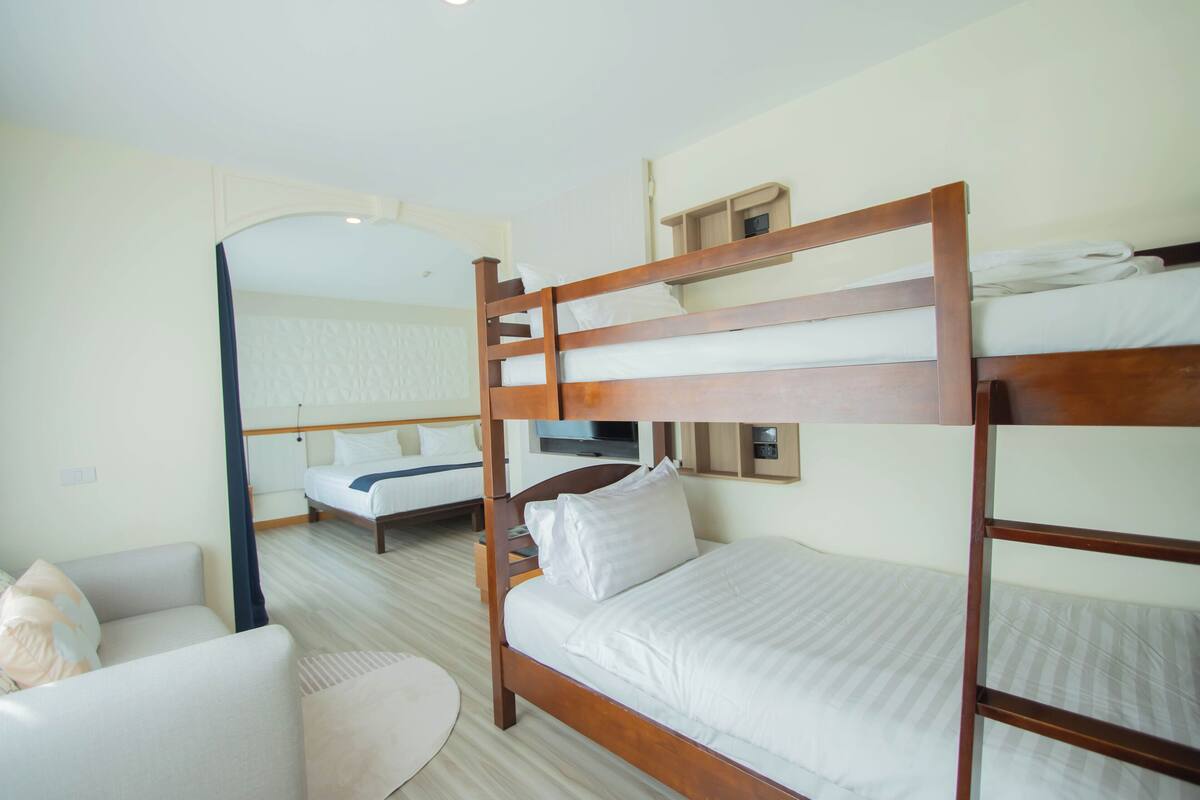 A hotel room with bunk beds, a sofa, and a television.