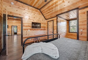 A wooden cabin with a bed, a television, and a sign that reads "treeline vacation rental." - Luxe 5-Bed Cabin with Hot Tub and Game Room (Broken Bow)