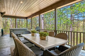 Eine überdachte Terrasse im Freien mit Esstisch, Korbstühlen und Grill.