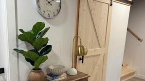 A wooden console table with a potted plant, a bowl, and books. A sliding barn door is visible in the background.