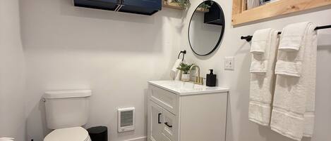 A bathroom with a toilet, sink, mirror, and towel rack.