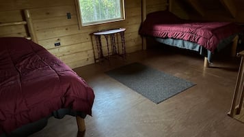 A cabin with two beds, a small table, and a window.