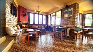 Un interior acollidor amb una llar de foc, mobles de fusta i grans finestres.