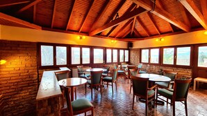 Un restaurant amb parets de maó, bigues de fusta al sostre i grans finestres. Taules i caires disposades per dinar.