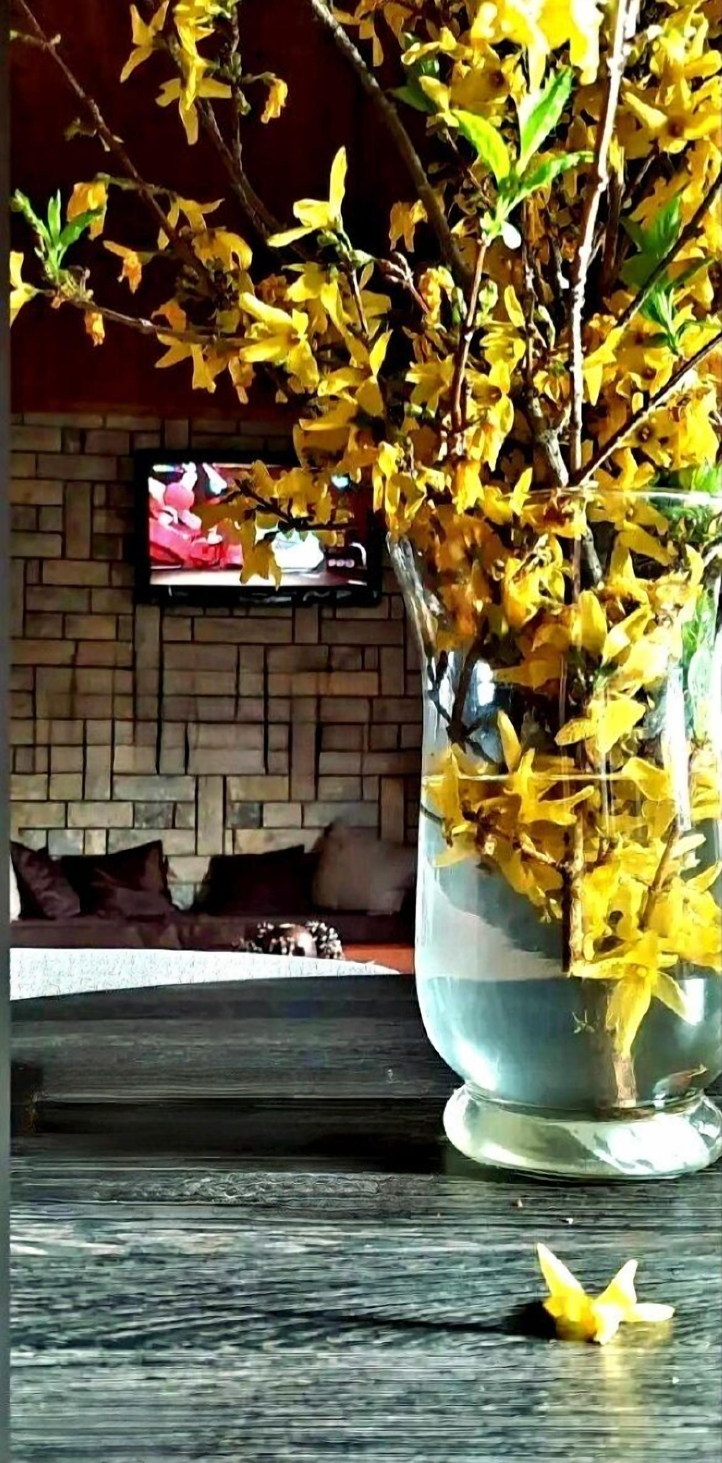 A large vase with yellow flowers on a wooden table.