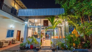 A modern house with a glass front, a balcony, and potted plants. - Lotus Bleu Guest House (Siem Reap)