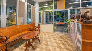 A room with a wooden bench and table, large windows with a view of the outside, and a decorative wooden shelf. - Lotus Bleu Guest House (Siem Reap)