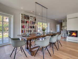A spacious dining area with a wooden table, modern chairs, and a bookshelf filled with books.